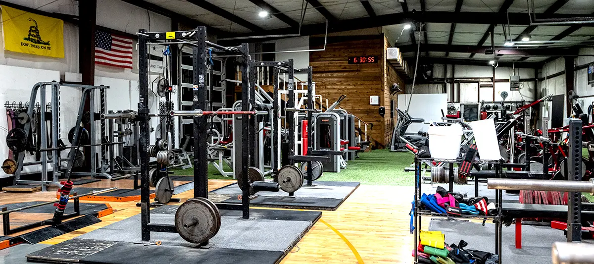 The platform end of the floor, with bumper plates stacked and a barbell loaded on the wood.
